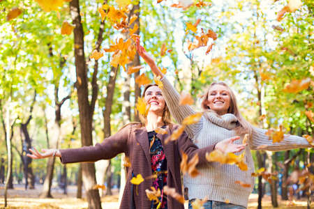 Fashionable beautiful young girlfriends walking together in the autumn park background. Having fun and posing. Toned in retro styleの写真素材