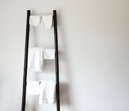 White towels hanging on rustic wooden ladder. Wall background with copy spaceの写真素材