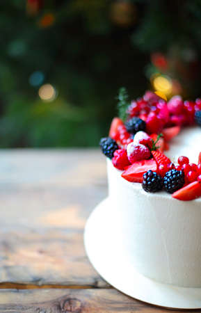 Christmas Cake decorated with berries by the Christmas treeの写真素材