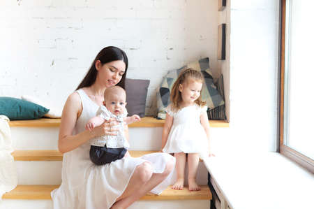 Happy young mother and cute little kids spending time together and smiling at cameraの写真素材