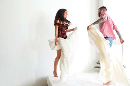 Young tattooed stylish couple in love hugging in bedroomの写真素材