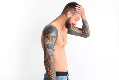 Fashionable shirtless man with tattoo posing in jeans, isolated on light backgroundの写真素材