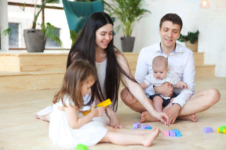 Happy family smiling while playing with colorful blocks at homeの写真素材