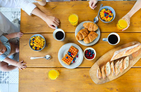 Happy family of four having breakfast In the kitchen. Top view