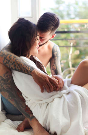 Young tattooed stylish couple in love hugging on the balconyの写真素材