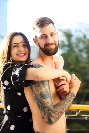 Young tattooed stylish couple in love hugging on the balconyの写真素材