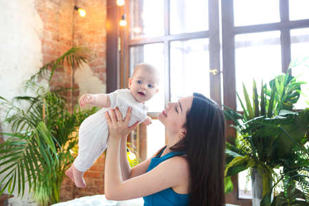Portrait of young mother with her adorable baby boy on bedの写真素材