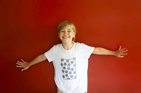Portrait of the pretty emothional child on a red background. Copy space, daylight