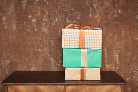 Stack of handcraft gift boxes on wooden board with a natural textured brown background の写真素材