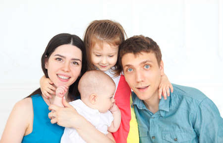 Happy young parents with their adorable little kids at home having fun togetherの写真素材