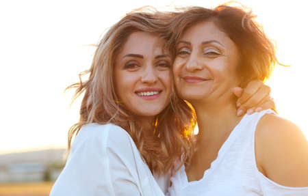 Two happy women in the lavander field. Middle age woman with her adult daughter in sunset lightの写真素材