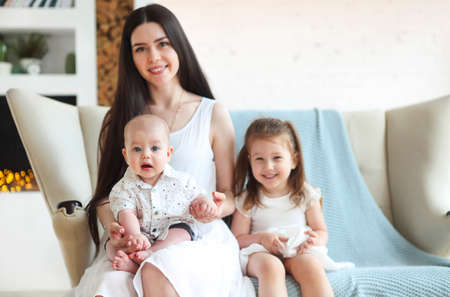 Happy young mother and cute little kids spending time together and smiling at camera
