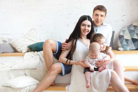 Happy young parents with their adorable little kids at home having fun together