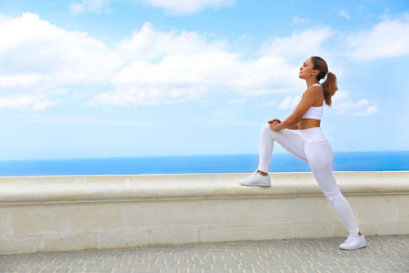 Beautiful young woman making stretching exercises in the beach