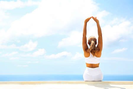 Beautiful young woman making stretching exercises in the beach