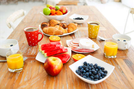 Coffee with fruit, cereal and croissant on wooden table background. Healthy breakfast