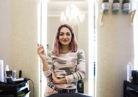 Smiling woman with bright hair working in hairdressing salon