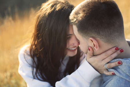 Romantic couple dressed in cozy sweaters together near the lighthouse on the sunset