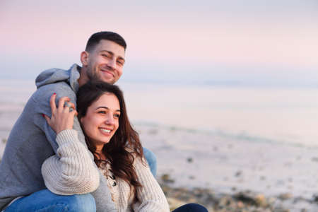 Young couple in love at rocky seacoast in sunset
