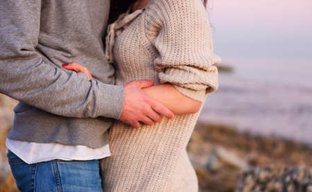 Young couple in love at rocky seacoast in sunsetの写真素材