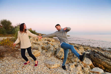 Young couple in love at rocky seacoast in sunsetの写真素材