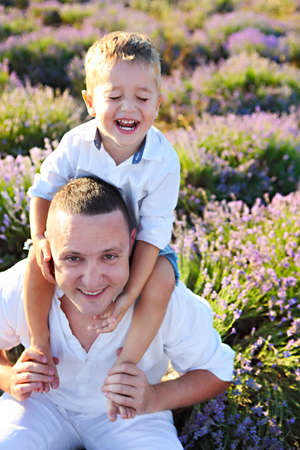 Young father hugging his little son, having fun together, and posing in a lavender fieldの写真素材
