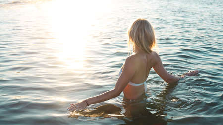 Beautiful young blond girl relaxing on a beach of tropical ocean, wearing stylish bikini