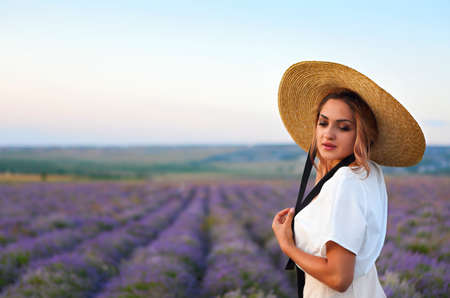 Beautiful young woman in straw hat in violet lavender fieldの写真素材