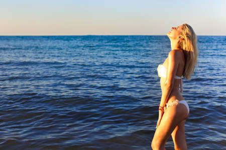 Beautiful young blond girl relaxing on a beach of tropical ocean, wearing stylish bikini の写真素材