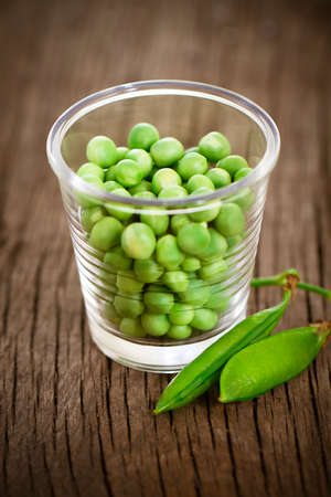 Fresh green peas in little glass on the rustic table. Close up 

の写真素材