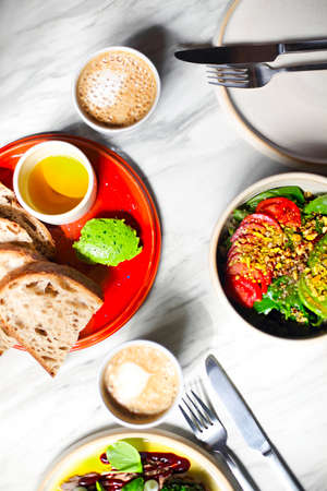 Top view of served green snack in bowl and plate of salad with cup of coffee on table