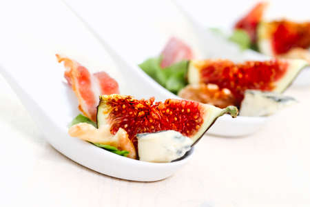 High angle closeup yummy breakfast including vivid red slices of ripe figs and piece of cheese in...