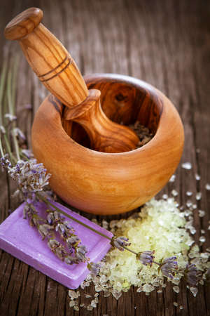 From above composition with natural handmade soap with lavender and sea salt placed next to wooden mortar with pestle on wooden backgroundの写真素材