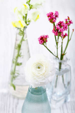 Beautiful natural flowers with delicate petals placed in glass vases with water