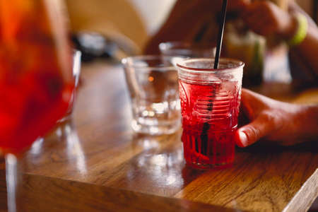 Unrecognizable person sitting at table and enjoying cool fruit cocktail on summer day in cafeteriaの写真素材