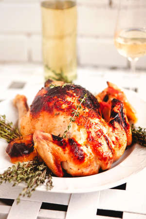 From above of appetizing grilled chicken decorated with dried rosemary on white plate in restaurant
