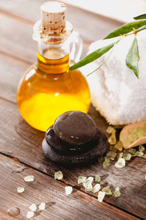 From above smooth pebbles and soft towel placed on lumber table near fresh olive oil and salt in spa salonの写真素材