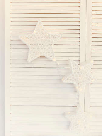 Set of decorative white Christmas stars with lights on white wooden shuttered background