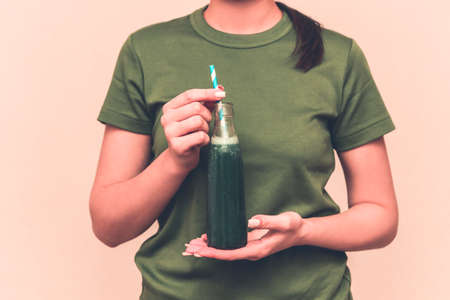 Happy brunette woman drinking fresh raw green detox vegetable juice. Healthy lifestyle, vegetarian food and meal, diet. Drink smoothie. Nutrition concept. の写真素材