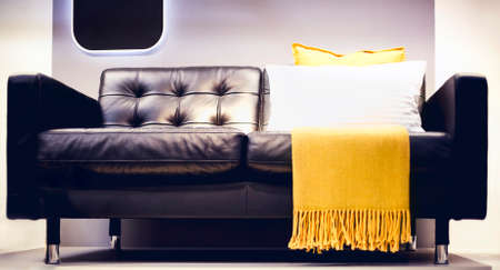 Living room interior with black sofa and yellow pillows on it. Cozy background
