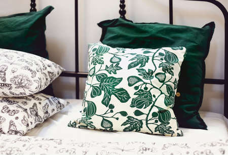 Set of various pillows with different natural ornaments and colors arranged on bed in modern apartmentの写真素材