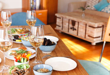 High angle of wooden table served with various homemade dishes and glasses with wine in cozy living room at homeの写真素材