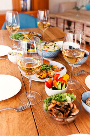 High angle of wooden table served with various homemade dishes and glasses with wine in cozy living...