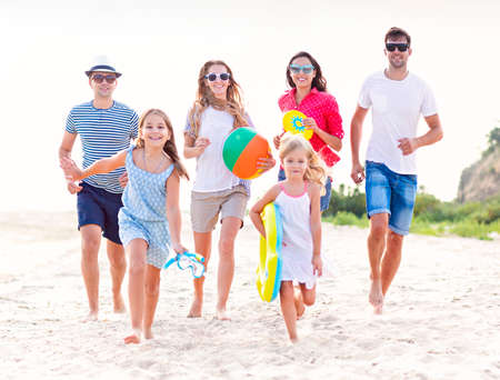 Multiracial group of friends with children running at the beach. Travel, fun and holiday conceptの写真素材