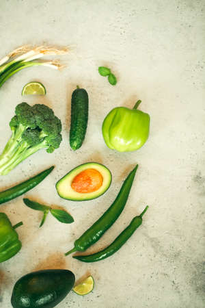 Top view of assorted fresh green vegetables placed on stone table in kitchenの写真素材