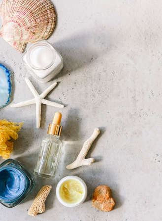 Top view of various cosmetic products in jars arranged on table with seashells and mineral stone