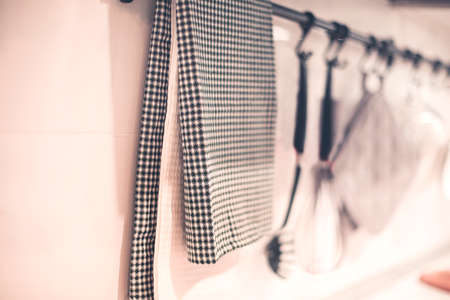 Closeup of textile napkin hanging on metal railing with assorted utensils near wall in contemporary kitchenの写真素材