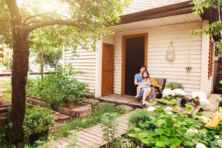 Beautiful woman with cute little child relaxing in garden while spending weekend in countrysideの写真素材