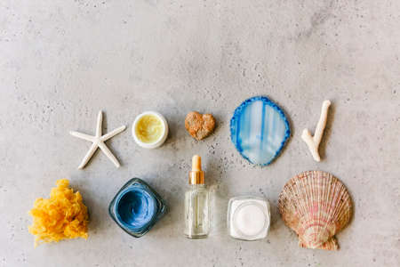 Top view of various cosmetic products in jars arranged on table with seashells and mineral stoneの写真素材