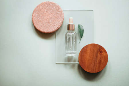 Top view of bottle of essential oil placed on wooden circles near fresh leafの写真素材